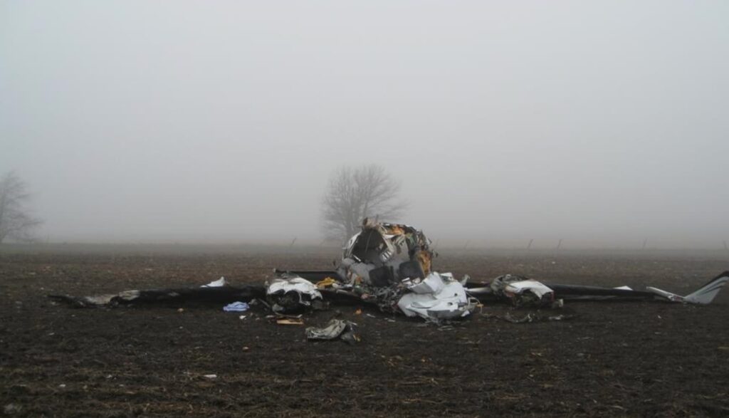 Frontal view of destroyed Cessna 414A fuselage in a foggy field, showing extensive damage and zero visibility conditions.